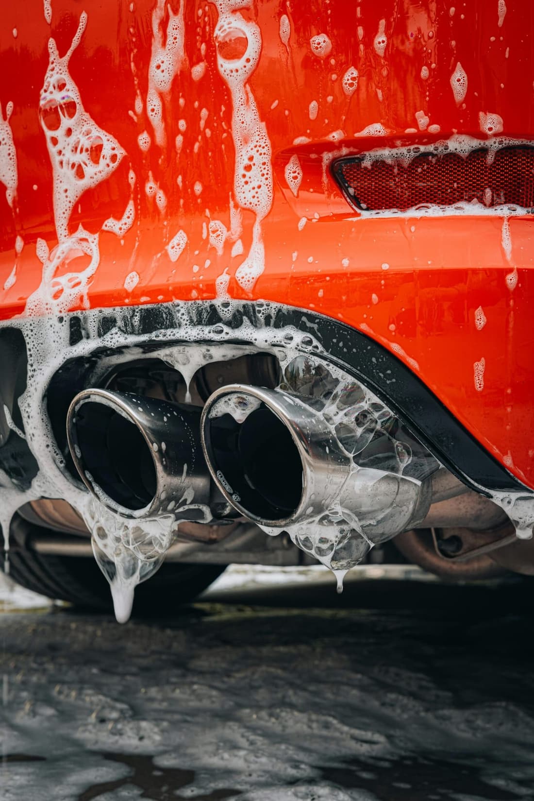 Bottom view of a soapy car exhaust during a professional detailing session by Premier Autos Detailing in West Plains, MO.