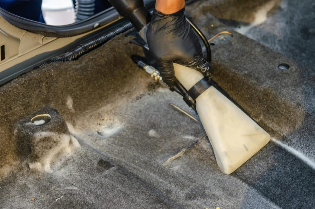 Technician deep-cleaning car carpet with extraction tool to remove extreme odors and stains in West Plains MO