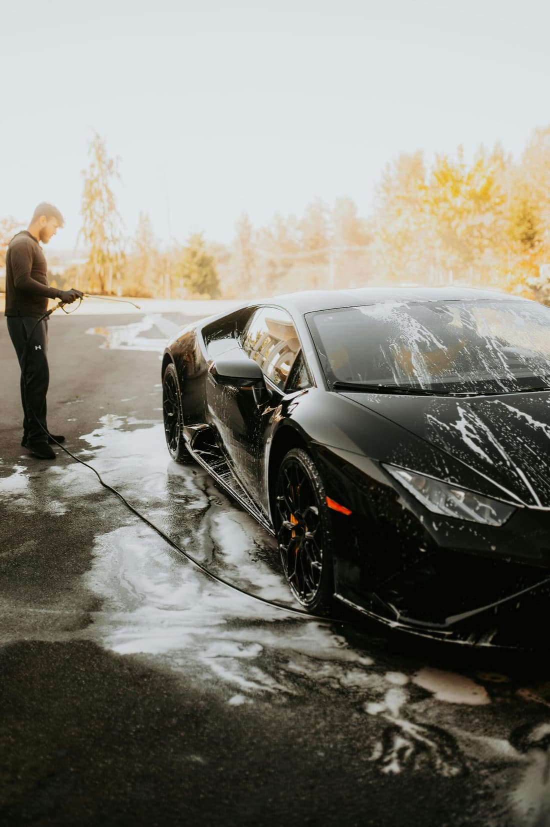 Mobile car detailing professional washing a luxury black sports car with foam at home in West Plains, MO – Premier Autos Detailing