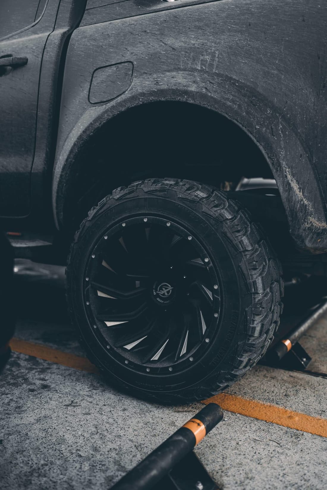 Close-up of a mud-covered off-road truck tire with a rugged black alloy rim.