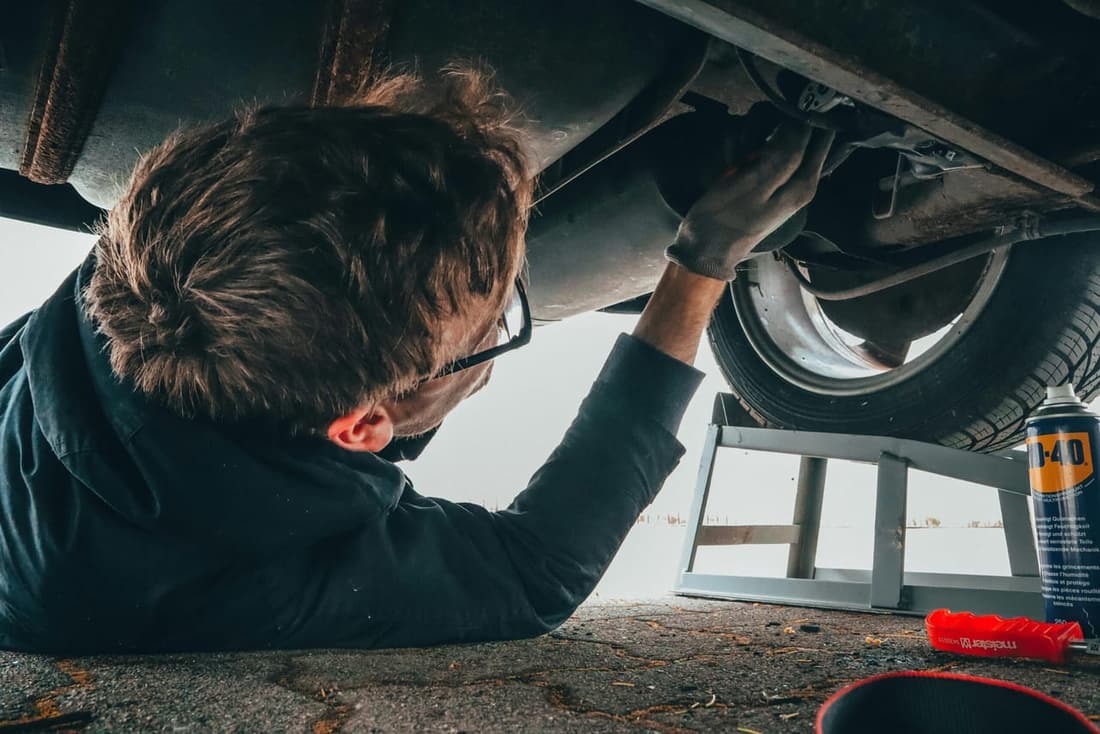 Man inspecting undercarriage of a vehicle on a ramp for detailing and rust prevention in West Plains MO