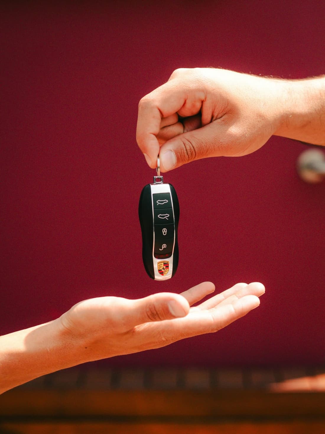 A clean Porsche key being handed over, symbolizing the impact of car detailing on resale value – Premier Autos Detailing, West Plains MO.