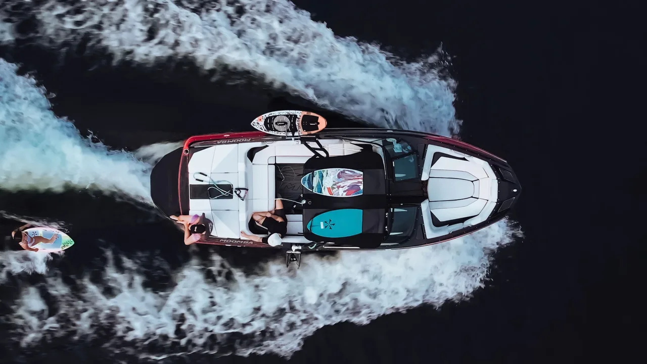 Aerial view of a wakeboard boat throwing a wake on a dark Ozarks lake, illustrating boat detailing near Bull Shoals Lake