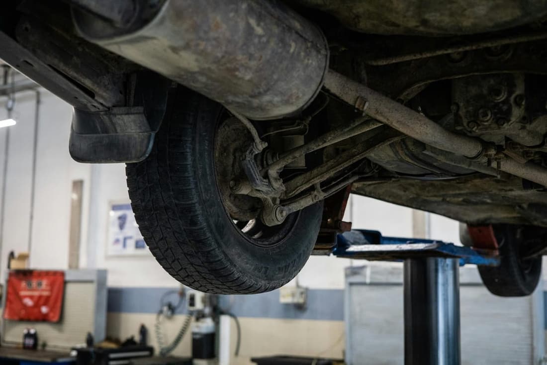 Close-up of a vehicle’s undercarriage with visible dirt and corrosion, taken in a professional detailing shop in West Plains, MO.