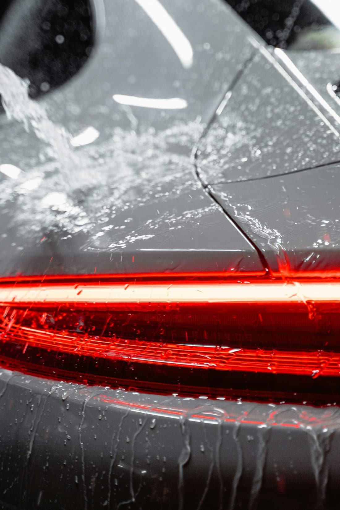 "Water cascading over a Porsche taillight, showcasing Premier Autos Detailing’s expert care and protective services in West Plains, MO."