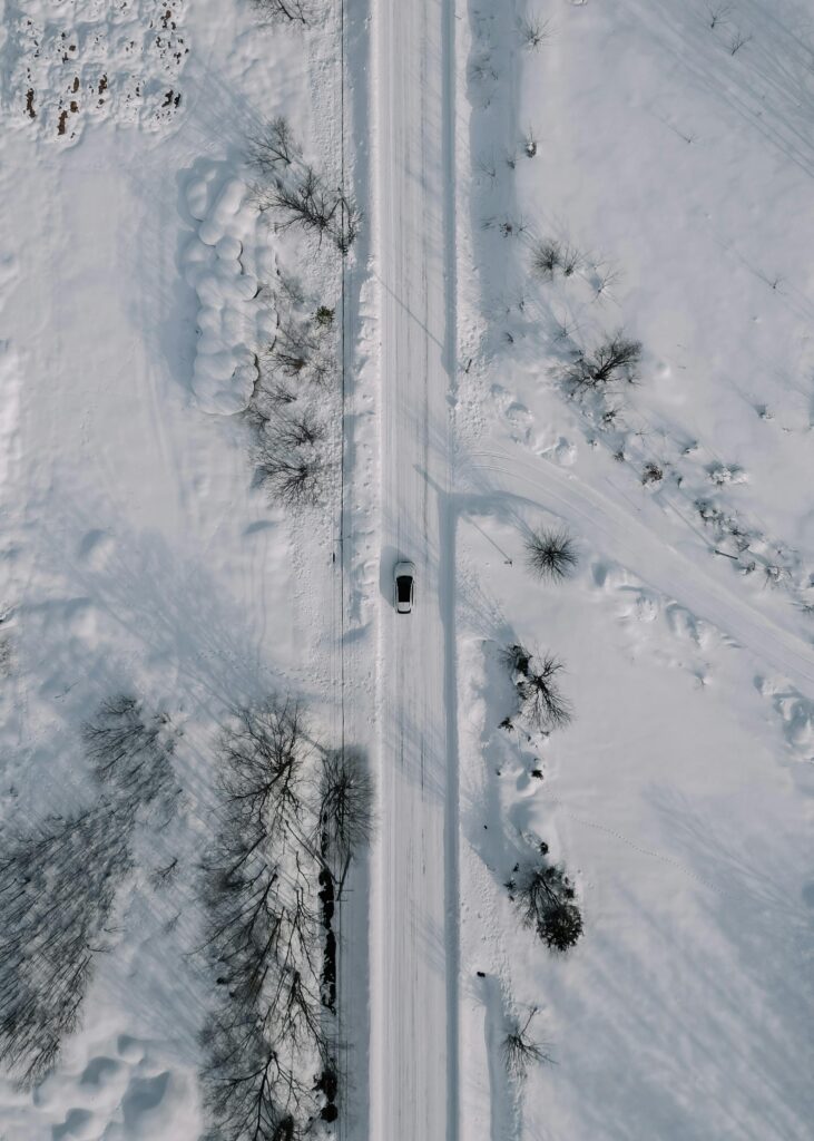 "A car driving through a snow-covered road, highlighting the need for winter detailing services from Premier Autos Detailing to protect and maintain its condition."