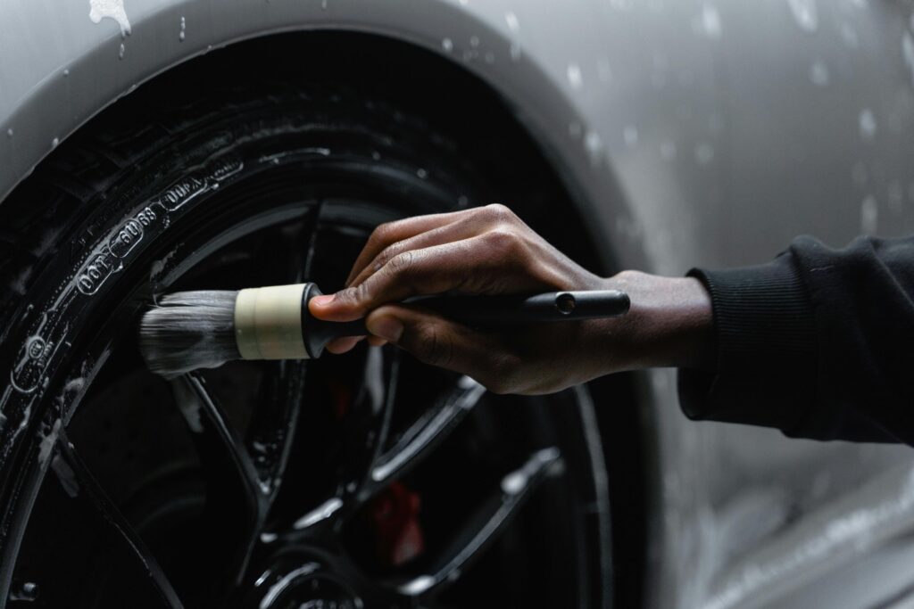 A car rim being carefully cleaned with a detailing brush by Premier Autos Detailing, showcasing expert care and precision for a spotless finish.