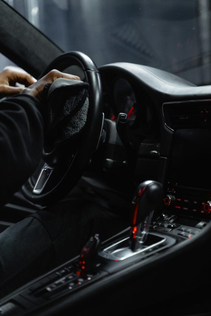 "A Premier Autos Detailing technician carefully wipes down a vehicle's steering wheel, ensuring a spotless and sanitized interior."