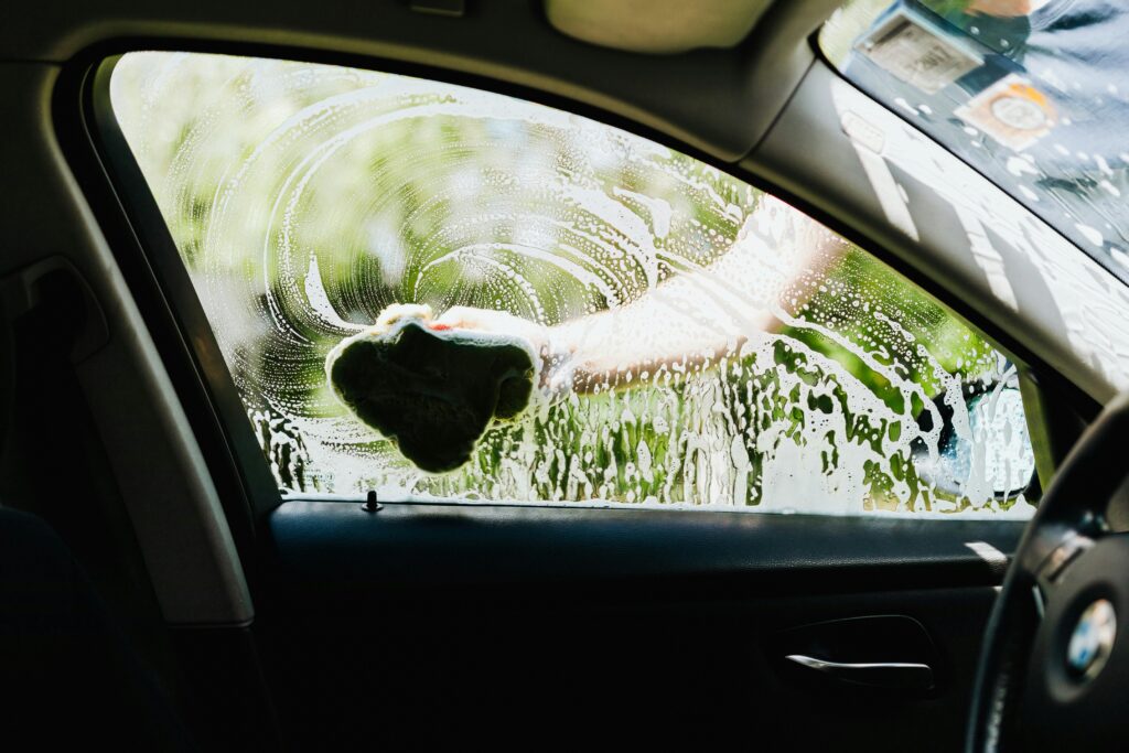 "Ceramic coating preparation": A car being hand-washed with a sponge before ceramic coating application.