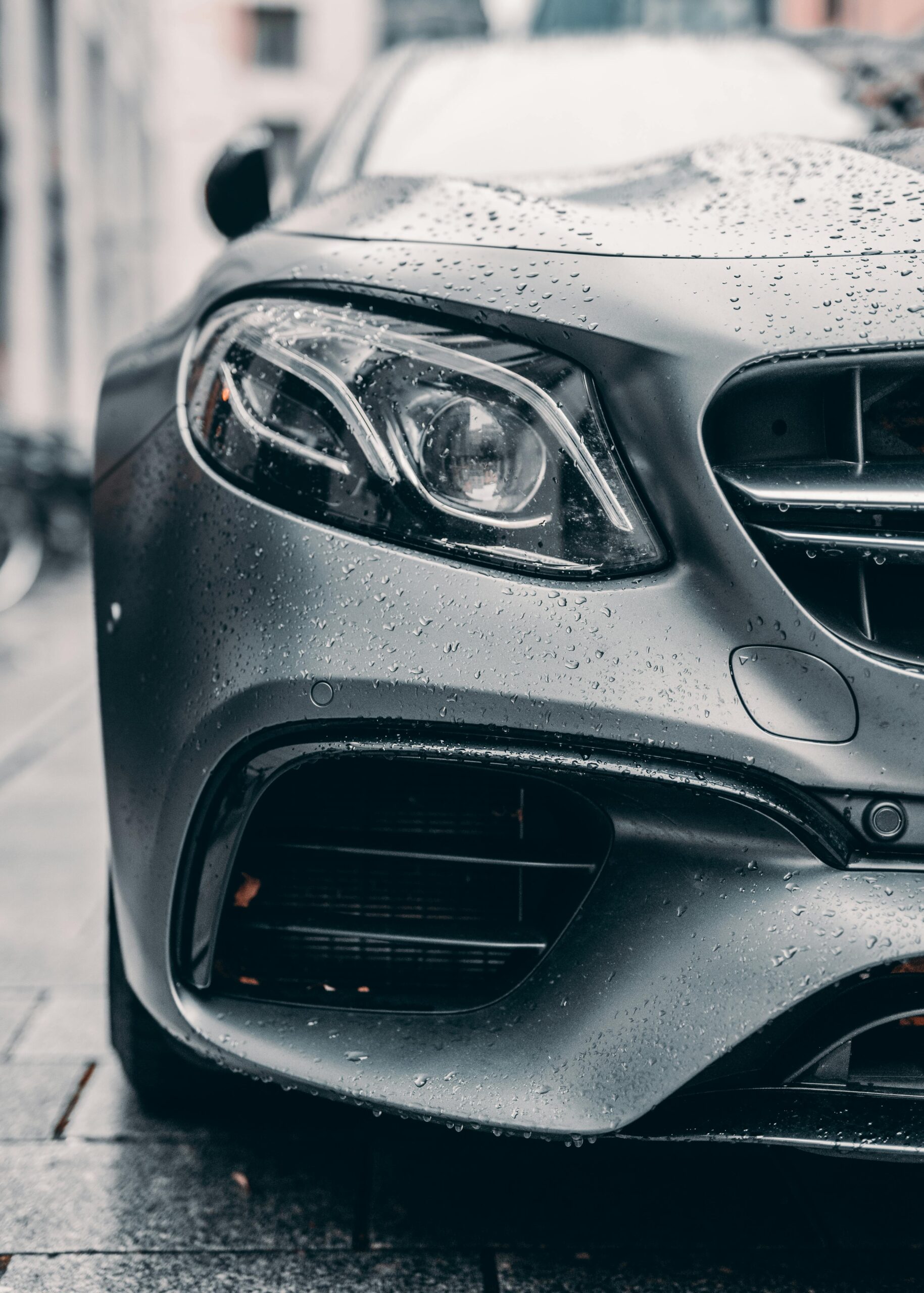 pexels-krislucas90-3264504 "Low-angle view of a wet grey Mercedes front left headlight, freshly washed and glistening, showcasing professional detailing results by Premier Autos Detailing."