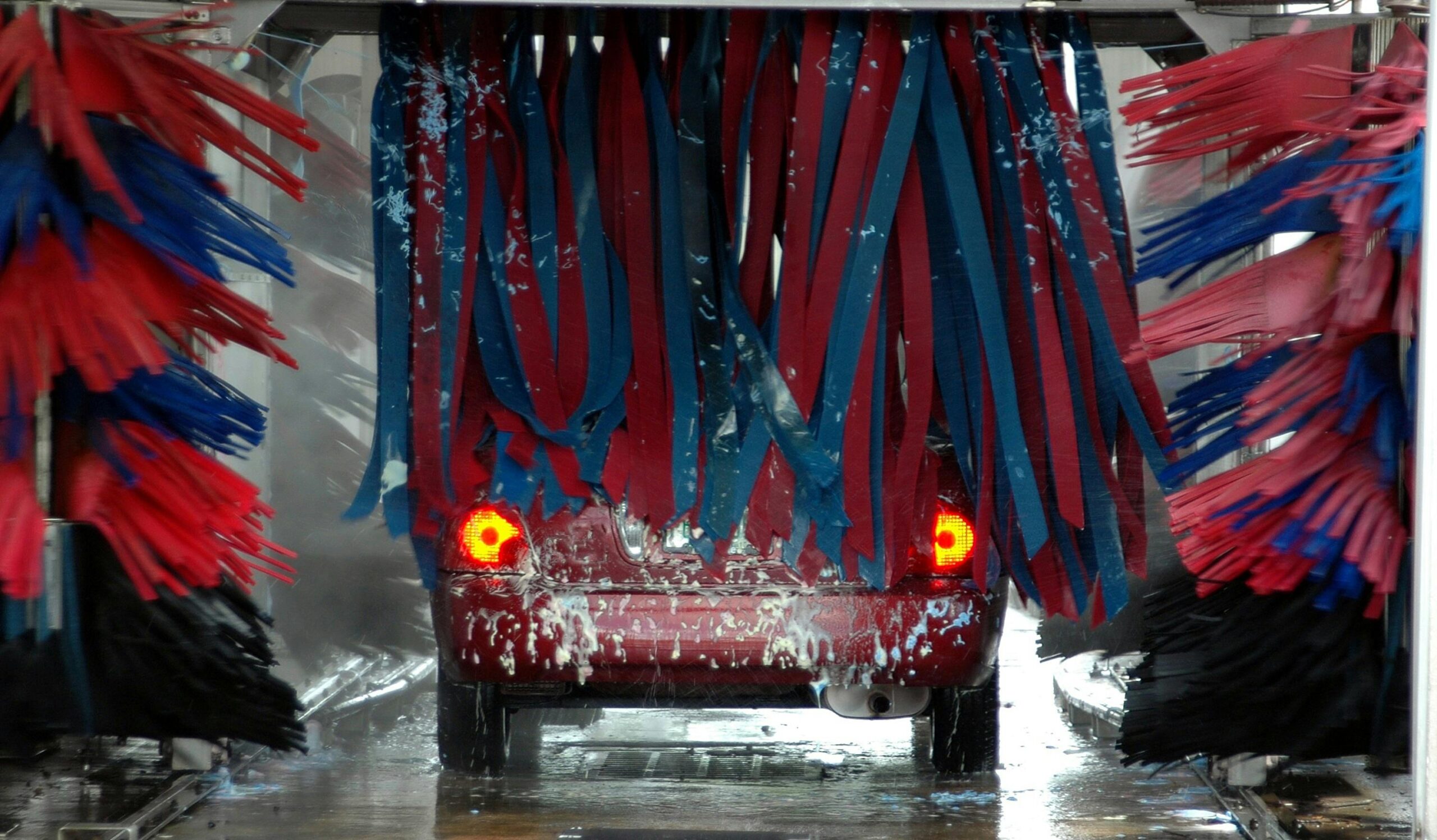 pexels-pixabay-210627 "Red car going through an automated car wash with rubber washers, highlighting the difference between automated washes and professional detailing services."