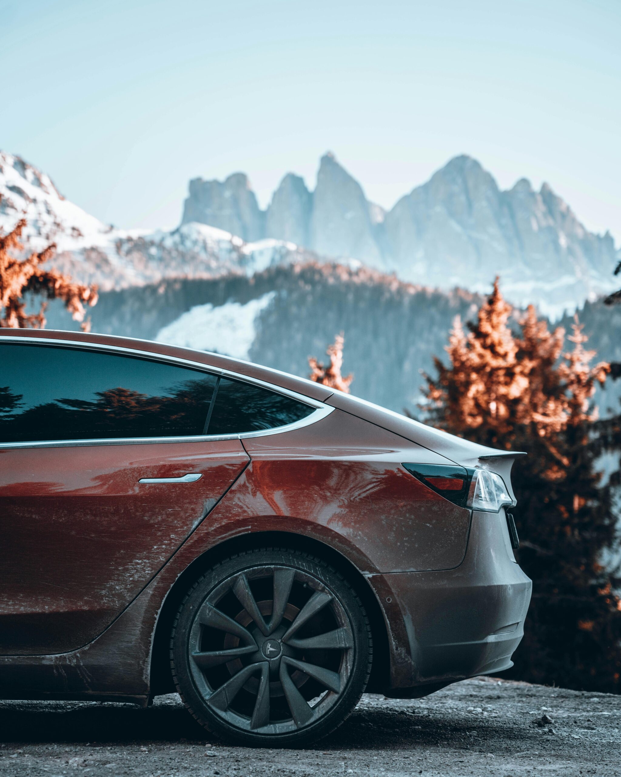 pexels-pixels-elements-14675274 A red car covered in winter grime parked in a mountain landscape, showcasing the need for professional detailing after harsh seasonal conditions.
