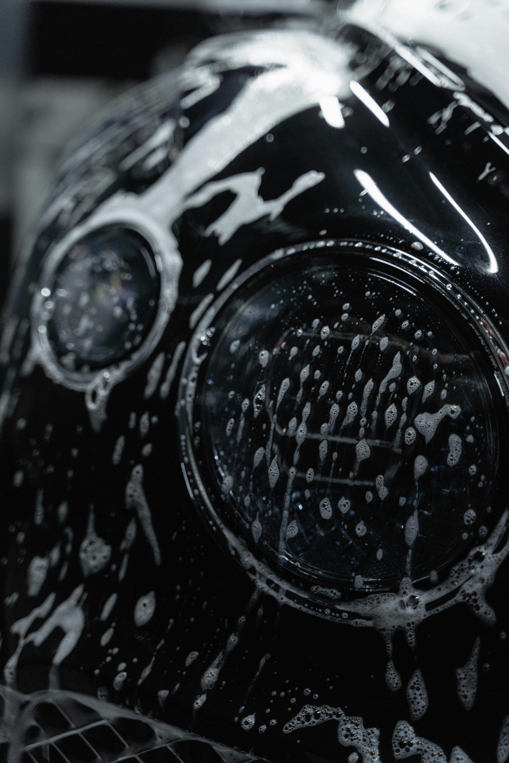 pexels-tima-miroshnichenko-6872149 Close-up of a Bentley's headlight covered in rich car shampoo foam, showcasing Premier Autos Detailing's expert car care services in West Plains, MO.