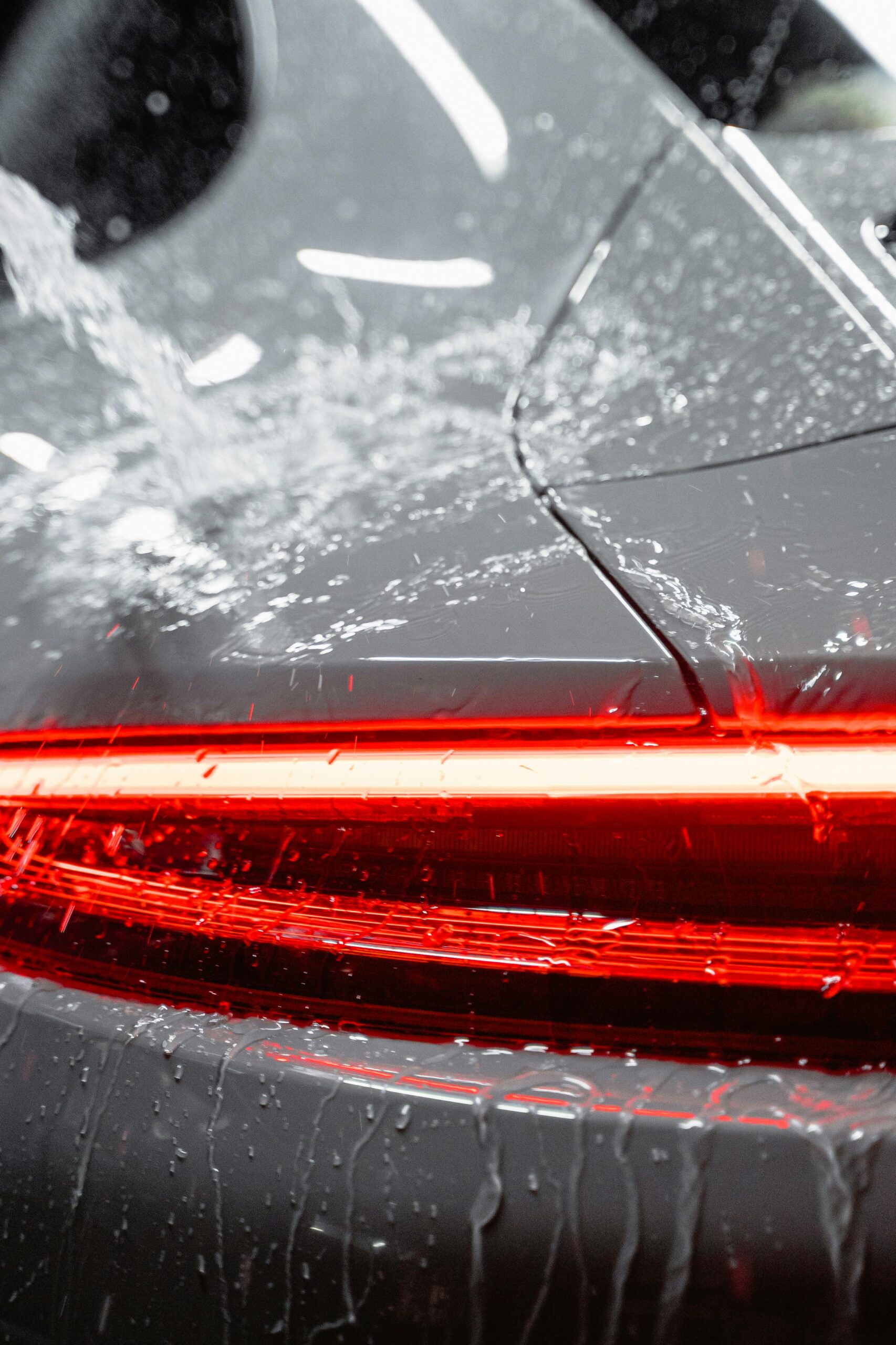 pexels-tima-miroshnichenko-6872151 "Water cascading over a Porsche taillight, showcasing Premier Autos Detailing’s expert care and protective services in West Plains, MO."