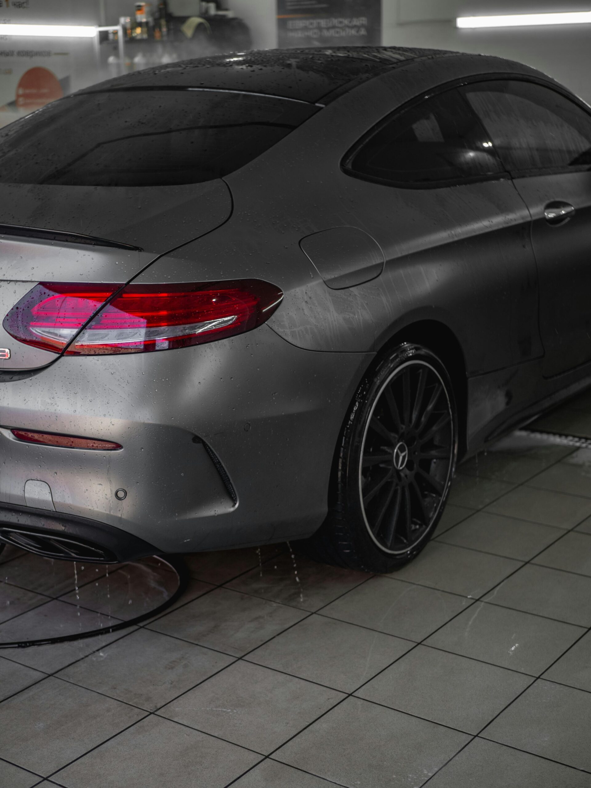pexels-vlad-52729368-12397895 A sleek, matte-gray Mercedes-Benz coupe with water droplets on its surface after a professional car wash.