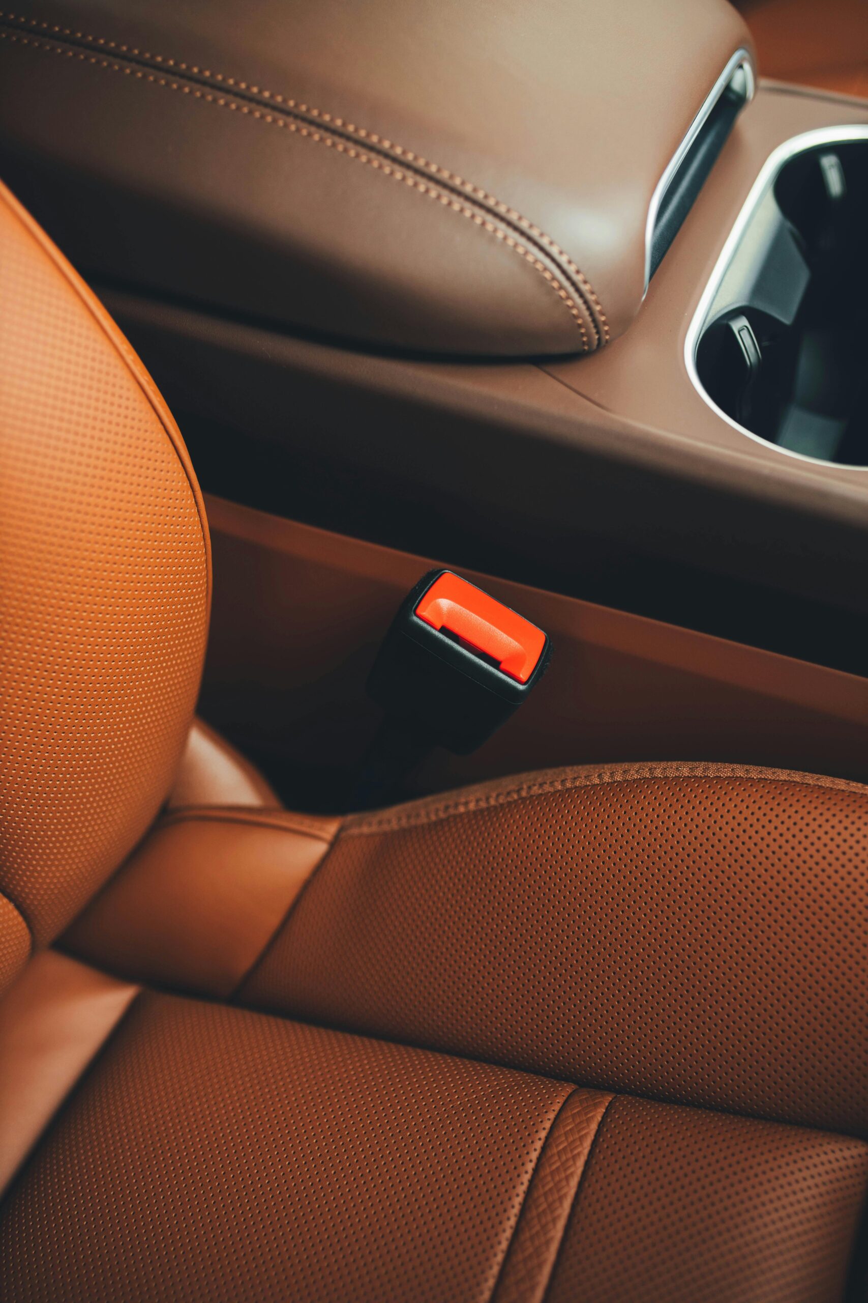 pexels-mohit-hambiria-92377455-17339319 Brown car seat with seat belt buckle close-up, showing detailed interior cleaning