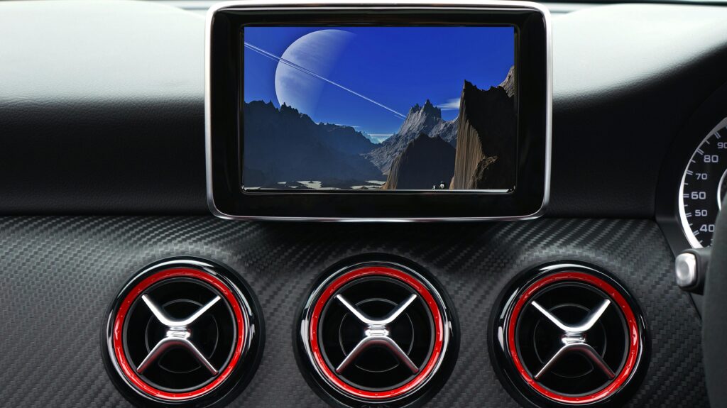 Close-up of a car's air vents and infotainment screen, emphasizing a sleek, clean dashboard with a futuristic display.