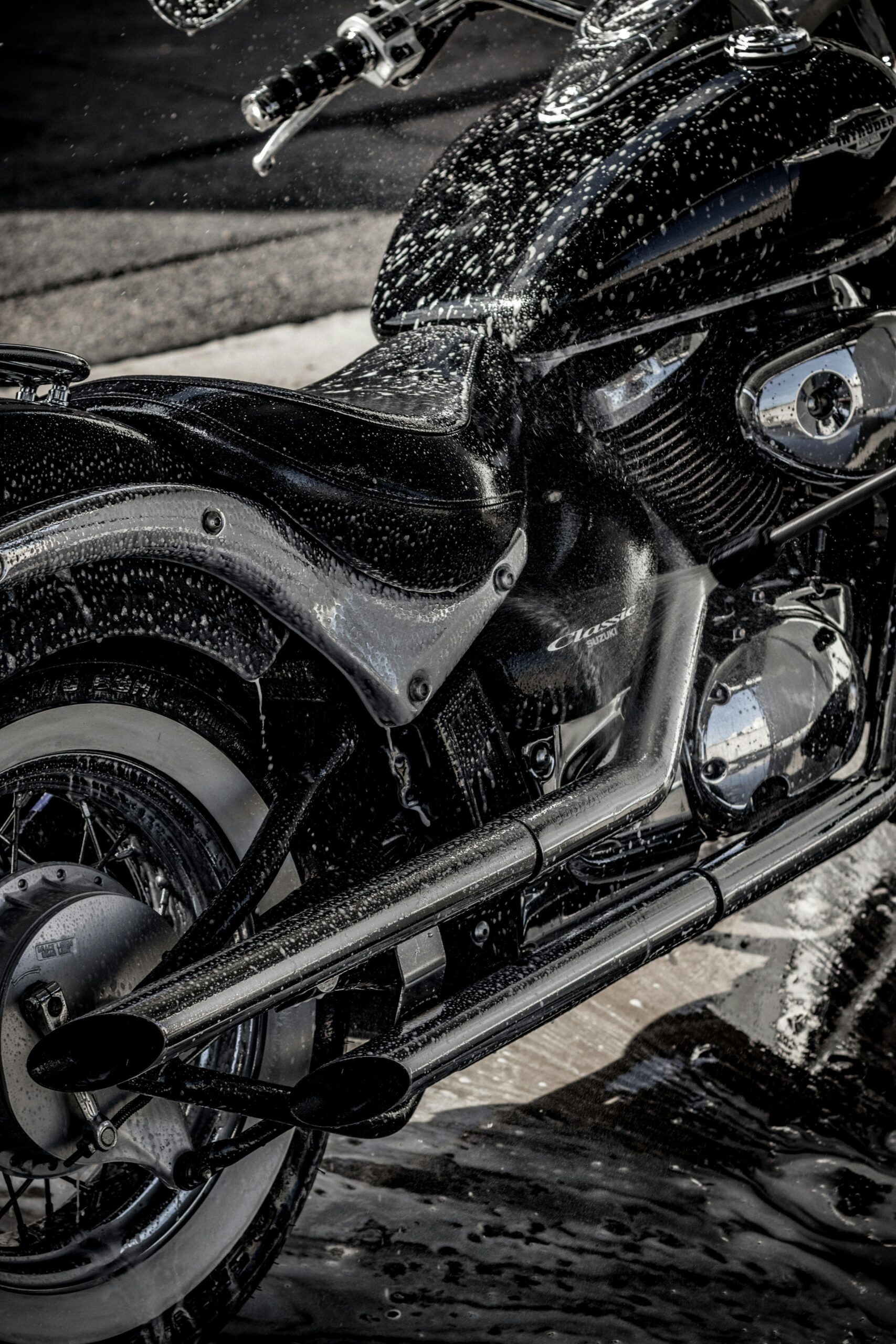 pexels-vanyaoboleninov-4513014 Close-up of a black motorcycle being washed with soap and water, emphasizing professional detailing.