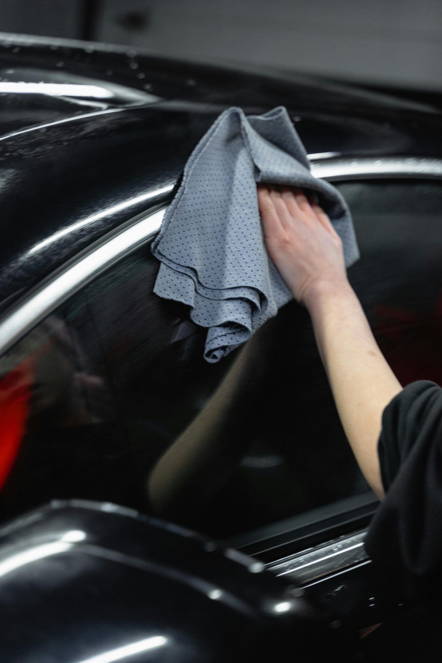 pexels-tima-miroshnichenko-6872570 Hand wiping a black car with a microfiber towel during full detail service