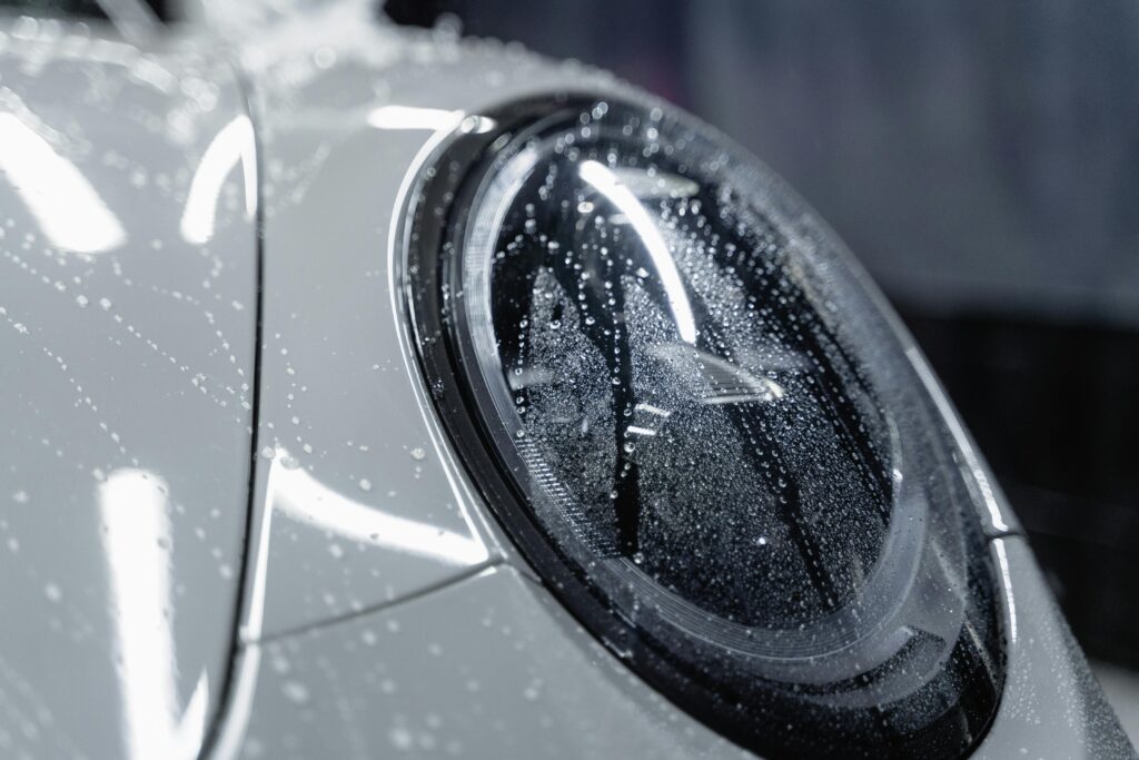 Close-up of a car headlight with water spots on the surface